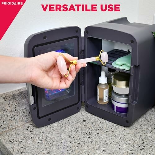 Open mini fridge with skincare products stored inside and a hand holding a facial roller